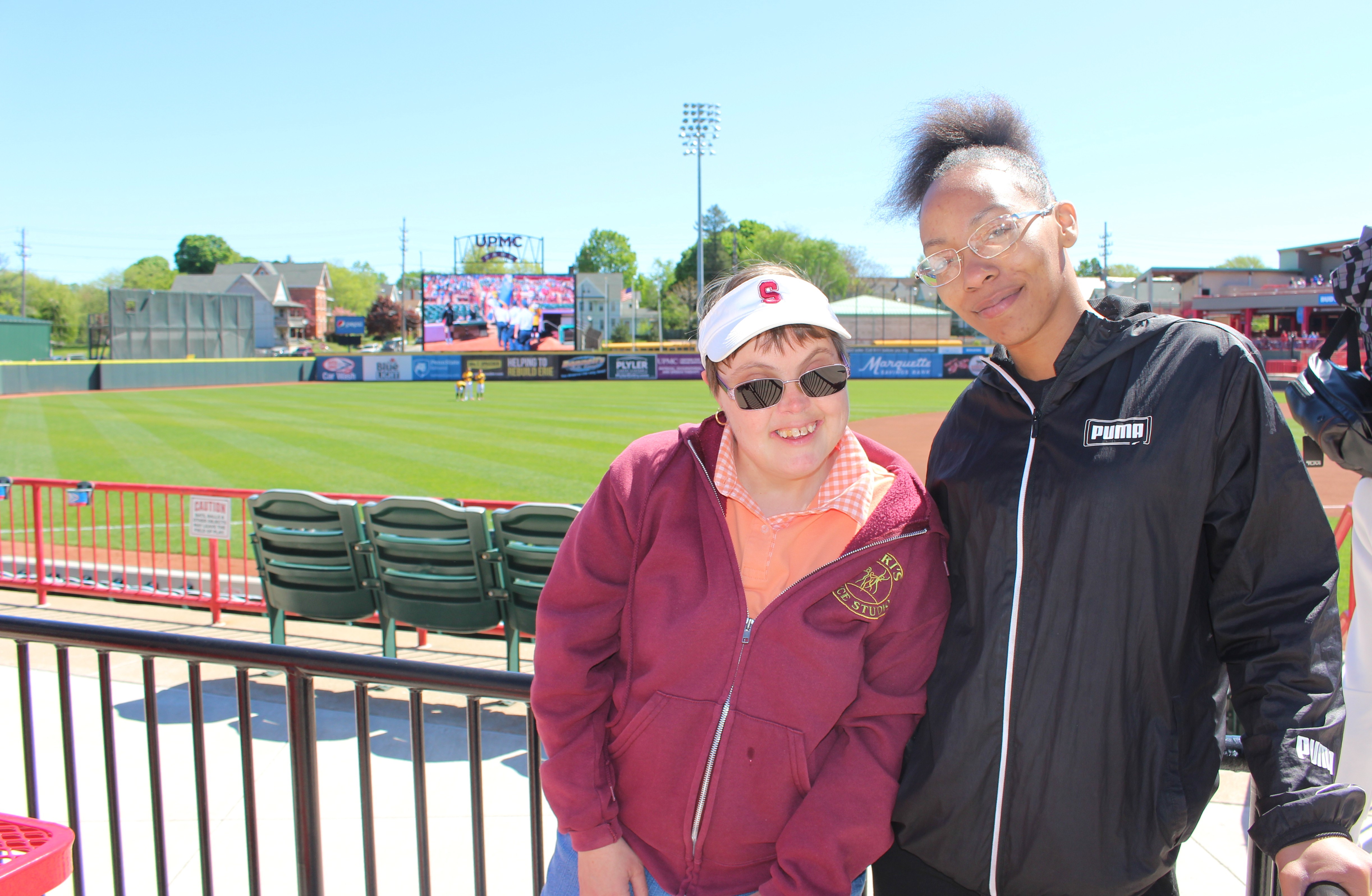 Two people standing in front of a baseball field