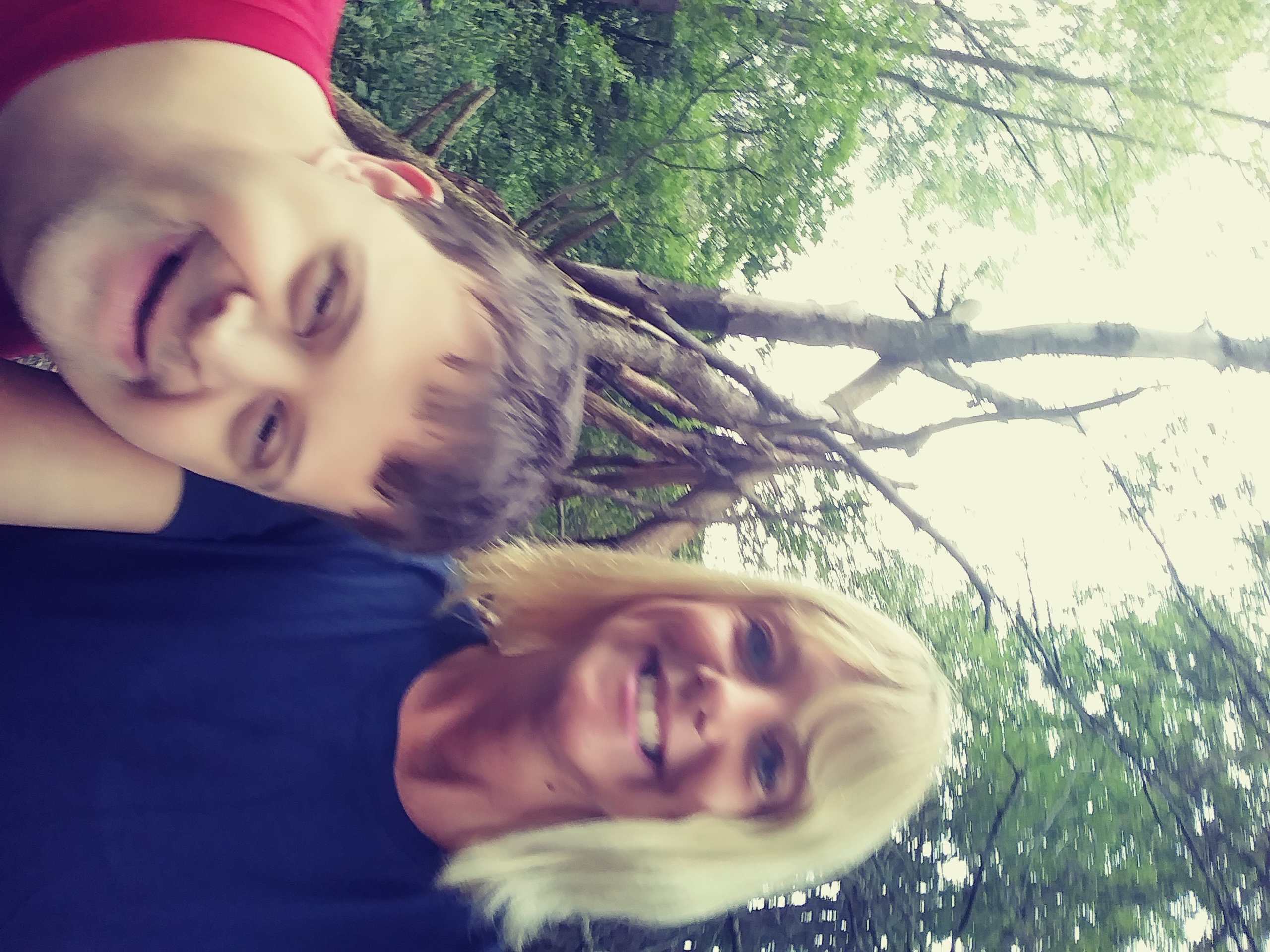 A man and a woman standing in front of a pile of sticks in the woods