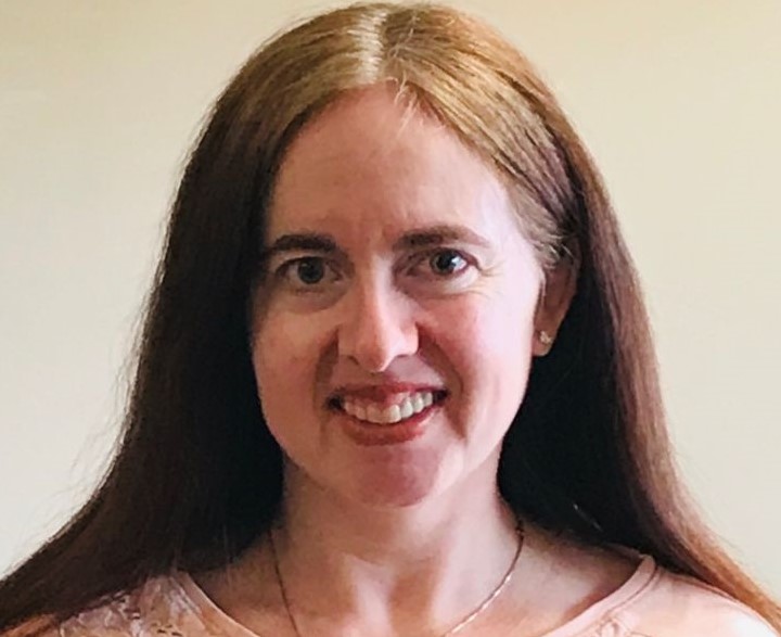 A woman with long, straight brown hair smiling at the camera